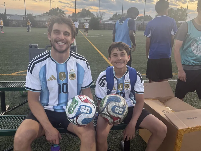 Coach and young player on the bench with soccer balls